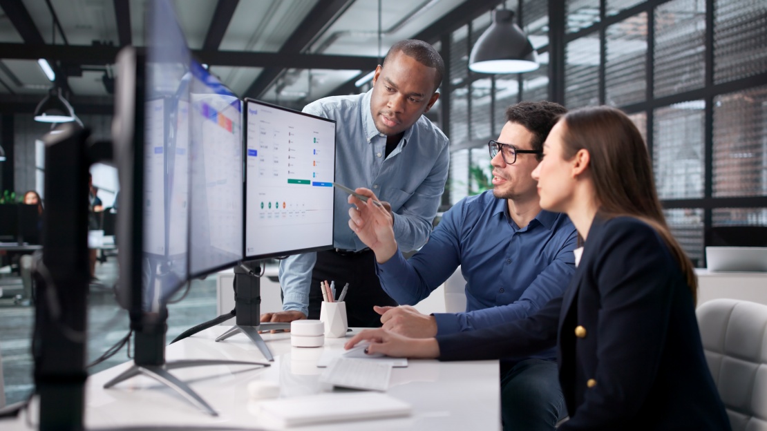 A man shows a chart to his colleagues to ensure procurement data quality.