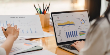 Employees analysing a financial report and dashboards to measure the impact of cost-push inflation on the company's profitability.