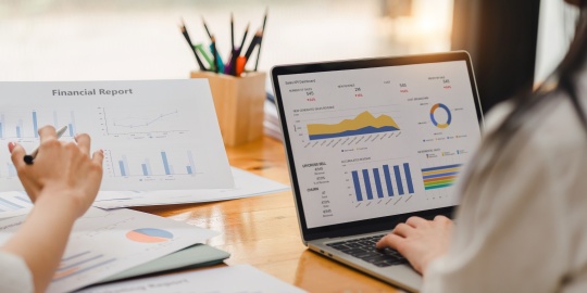 Employees analysing a financial report and dashboards to measure the impact of cost-push inflation on the company's profitability.