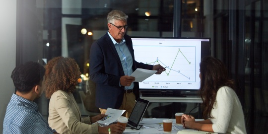 Two colleagues analysing dashboards to track and optimise the company's overhead costs.