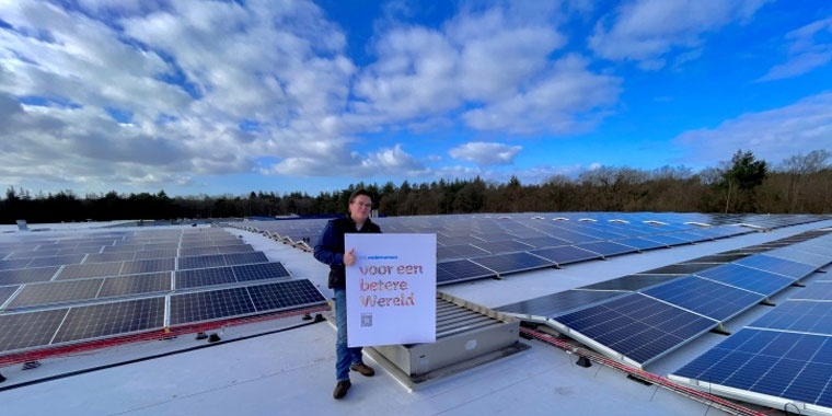 Photo of a Manutan Netherlands employee on a roof with several solar panels