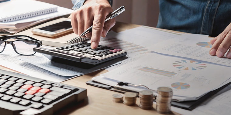 Image of a man using a calculator with coins