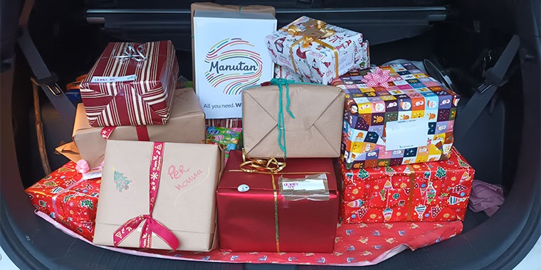 Plusieurs cadeaux dans un coffre de voiture, avec sur l'un d'eux le logo Manutan