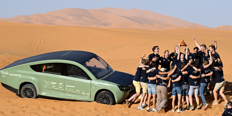 Photo de plusieurs personnes dans le désert et d'une voiture électrique