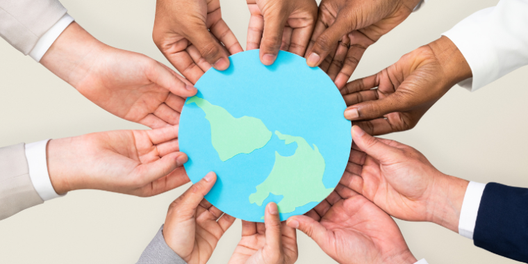 Hands joined around a paper Earth